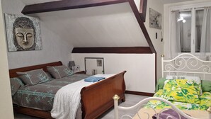 A bedroom with a wooden bed, a white metal bed frame, a wall-mounted Buddha sculpture, and a window with curtains. - "Buddha" Room—perfect for sporting events at the Le Mans circuit (Le Mans)