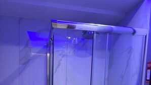 Une salle de bain moderne avec une douche à parois de verre, des toilettes et un mur en marbre.