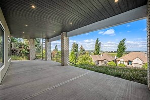 Ein überdachter Außenbereich mit Betonboden, Ziegelstützen und Blick auf Wohnhäuser.