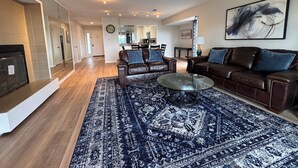 Ein großzügiges Wohnzimmer mit Kamin, Ledersofas, einem Couchtisch und einem großen Teppich.