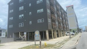Un edificio de varios pisos con fachada oscura, múltiples ventanas y balcones.