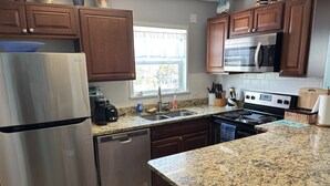 Una cocina con armarios de madera, electrodomésticos de acero inoxidable, encimeras de granito y una ventana con vistas.
