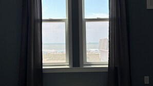 Una habitación con cama, ventana con cortinas y vista al mar.