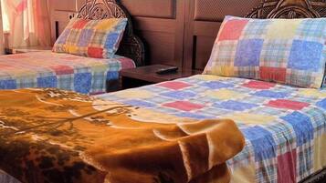 Een kamer met twee bedden, elk voorzien van een gewatteerde spreideken en een hoofdbord. Er staat een nachtkastje met een lamp en een afstandsbediening op.