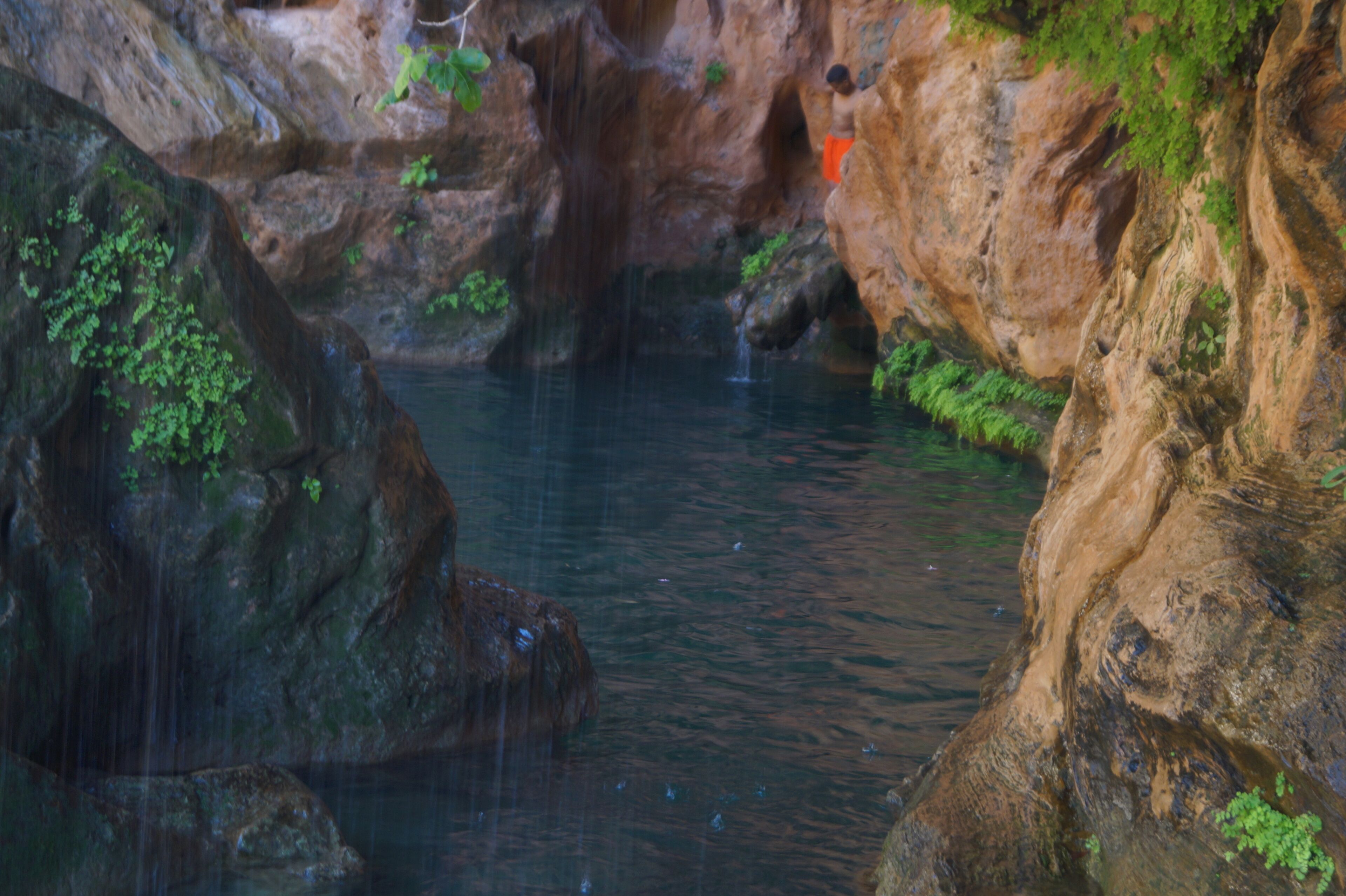 Una formación rocosa natural con una cascada pequeña y un estanque de agua.