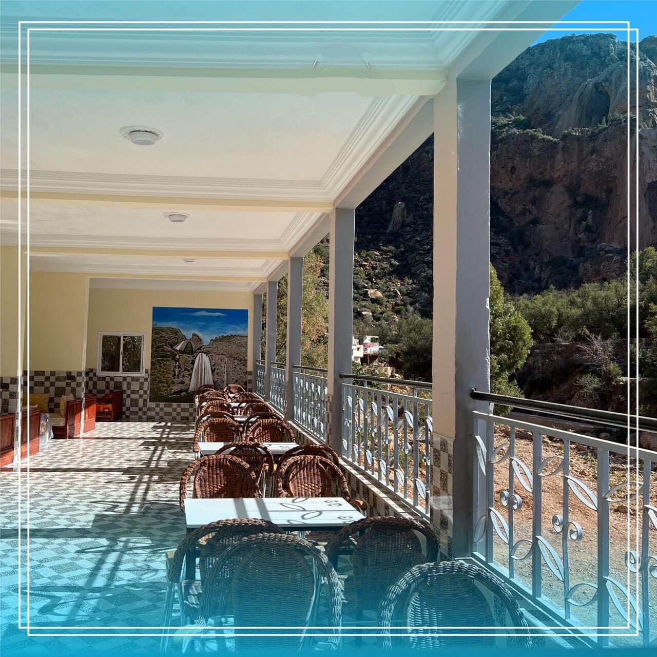Un espacio de estar techado al aire libre con mobiliario de mimbre, una piscina y vistas a un paisaje montañoso.