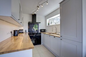 A modern kitchen with a wooden countertop, a stove, a microwave, and a window with a view. - Marmottes 3-Bed, 2-Bath - Walk to Spa & Village (Saint-Gervais-les-Bains)