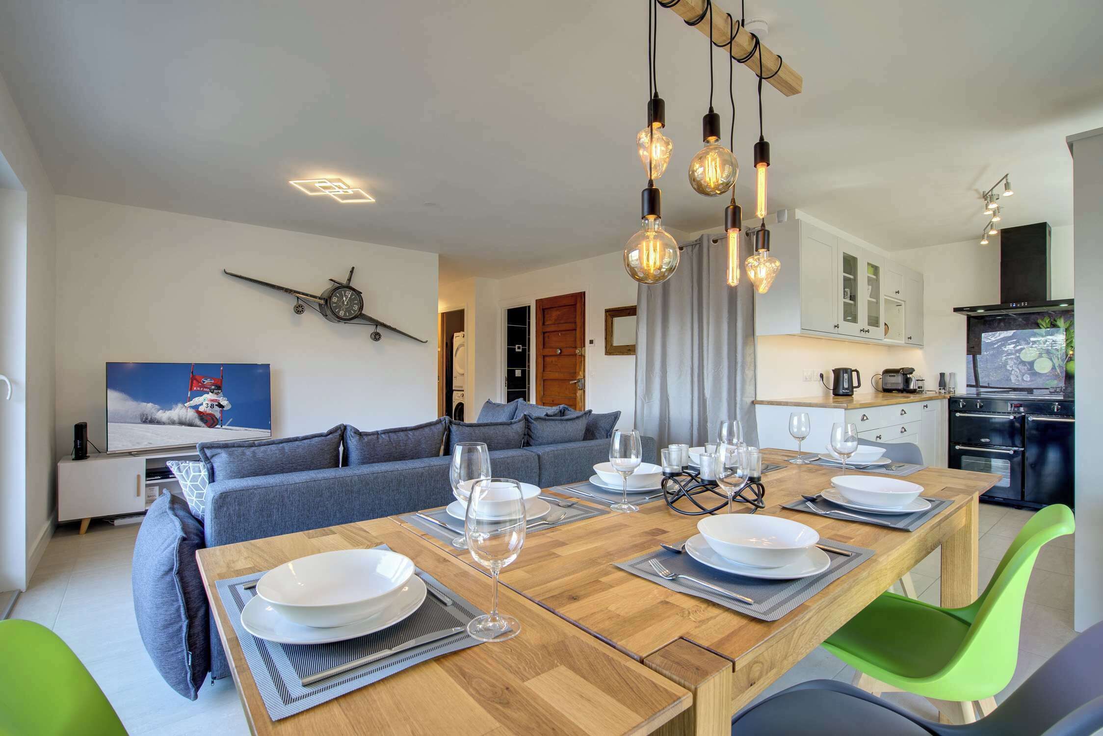 Una sala de estar moderna con comedor, cocina y un televisor que muestra un velero.