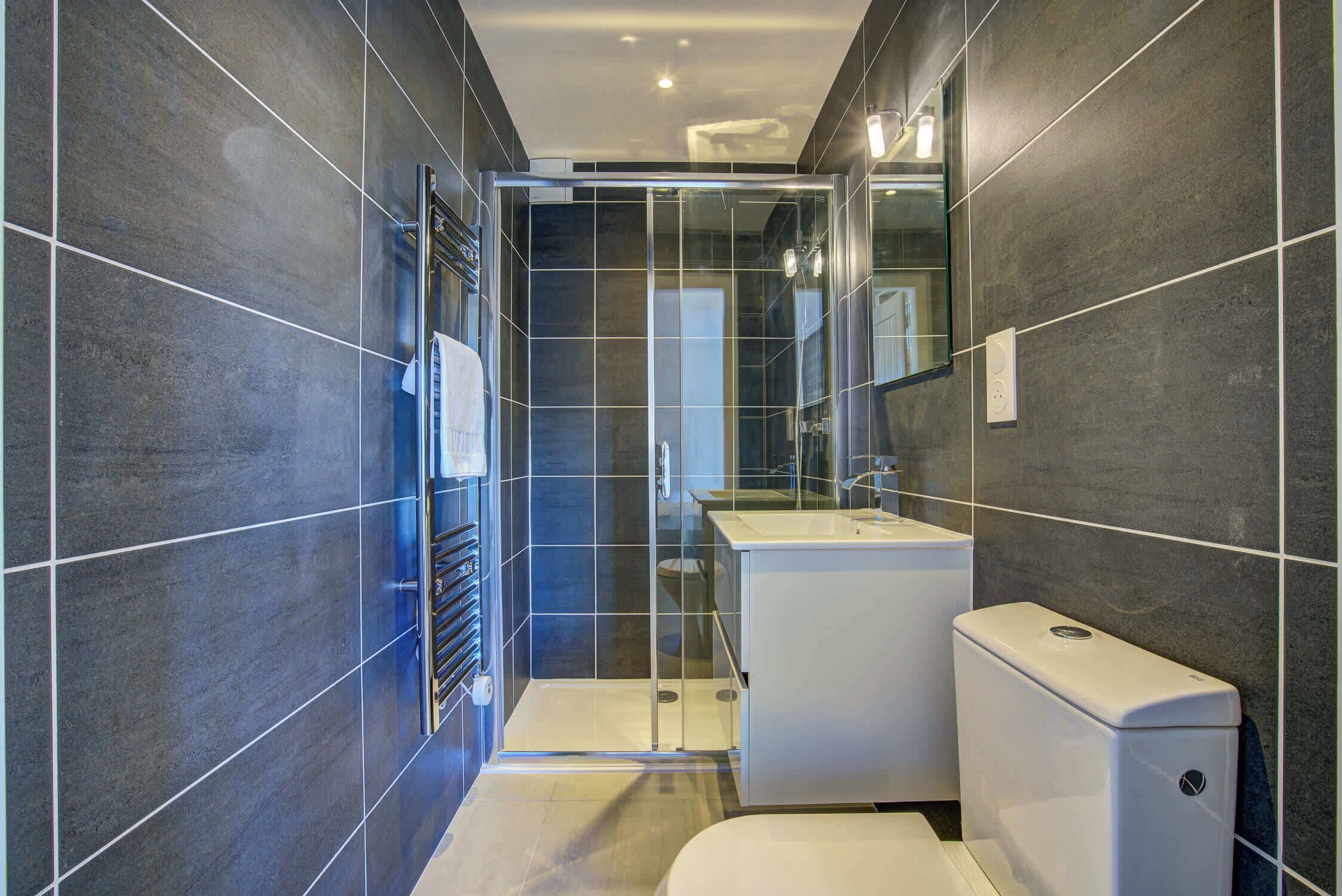 A modern bathroom with a glass shower enclosure, a white sink, and a toilet.