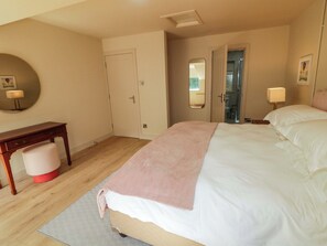 Ein Schlafzimmer mit Bett, Nachttisch, Sessel und Spiegel.