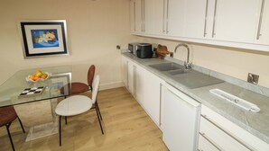 A modern kitchen with white cabinets, a glass dining table, and a microwave. - Suite 33B (Londonderry)