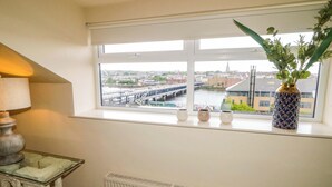 A room with a view of a bridge, a radiator, and a table with a lamp. - Suite 33B (Londonderry)