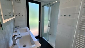 Un bagno moderno con due lavandini, cabina doccia in vetro e porta in vetro smerigliato.