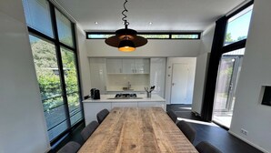 Una cucina moderna con mobili bianchi, un tavolo da pranzo in legno e una lampada a sospensione.