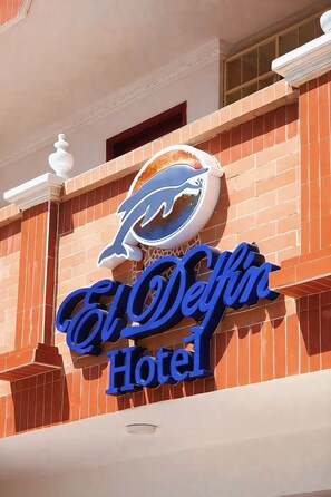 A hotel sign with a dolphin logo and the name 'El Delfino Hotel' in blue letters. - Delfin Hotel Collection Rodadero (Santa Marta)