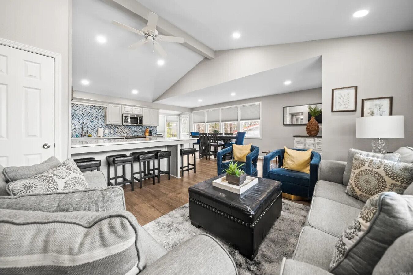 A spacious living area with a kitchen, a dining area, and a seating area with sofas and chairs.