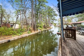 Une terrasse au bord de la rivière, offrant une vue sur le cours d’eau, entourée d’arbres et agrémentée d’un petit quai.