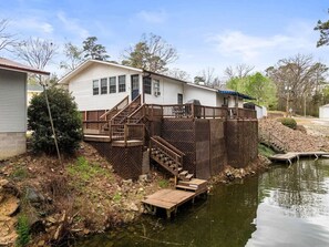 A house with a wooden deck, a staircase, and a dock extending into a pond. - Lakefront Retreat w/ Stunning Views | Hot Springs (Hot Springs)