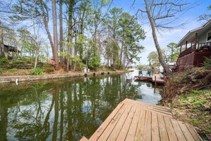 A wooden dock extending into a calm river, surrounded by trees and a building with a porch. - Lakefront Retreat w/ Stunning Views | Hot Springs (Hot Springs)