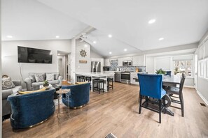 Une cuisine moderne avec des meubles blancs, un îlot central et un coin repas avec des chaises bleues.