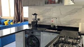 Een moderne keuken met een ingebouwde wasmachine, een fornuis en een groot raam.