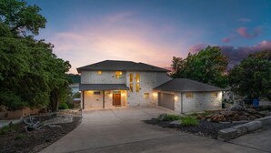 A two-story house with a stone facade, a front garage, and a driveway. - Lake House Dock Slip Heated Pool Boat Launch Beach Game Room (Leander)