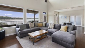 A spacious living room with a large sectional sofa, a wooden coffee table, and a ceiling fan. - Lake House Dock Slip Heated Pool Boat Launch Beach Game Room (Leander)