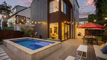 Een modern huis met een zwembad, buitenzitplaatsen en lichtslingers.