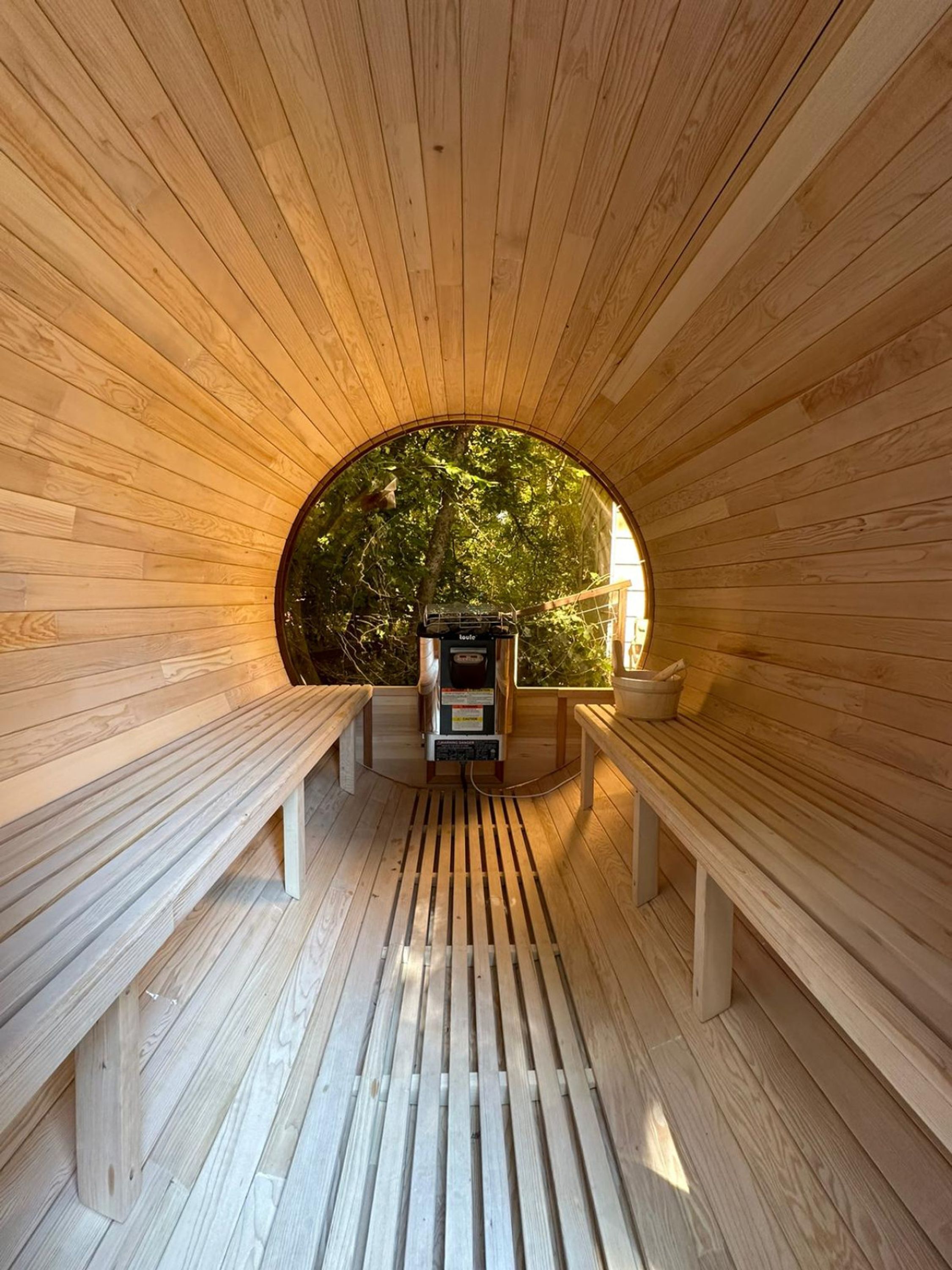 A wooden sauna with benches and a sauna machine.
