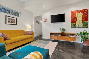 A living room with a sofa, a TV, a painting, and a plant. - Secluded Guest House in Beautiful Setting (Austin)