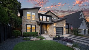 A modern two-story house with a stone facade, a front porch, and a well-maintained lawn. - Zilker Home With Heated Pool Hot Tub Walkable (Austin)