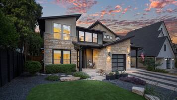 A modern two-story house with a stone facade, a front porch, and a well-maintained lawn.