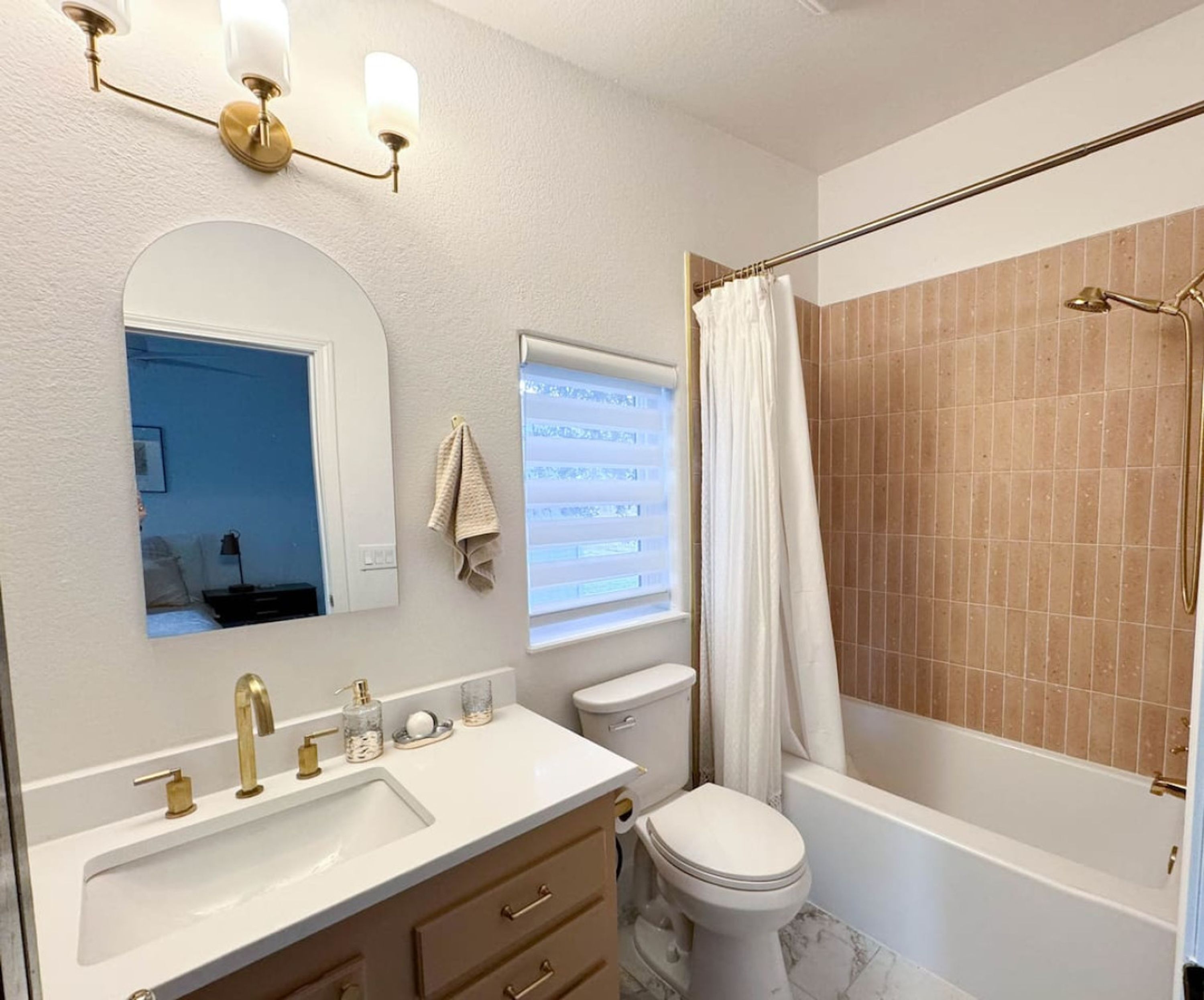 A bathroom with a sink, vanity, toilet, and bathtub.