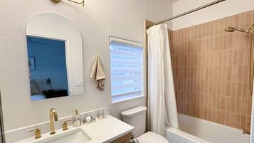A bathroom with a sink, vanity, toilet, and bathtub.