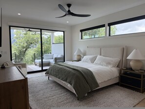 A bedroom with a bed, two bedside tables with lamps, a ceiling fan, a large window, and a sliding glass door leading to a balcony. - New Build Downtown Views Pool Spa Walkable (Austin)