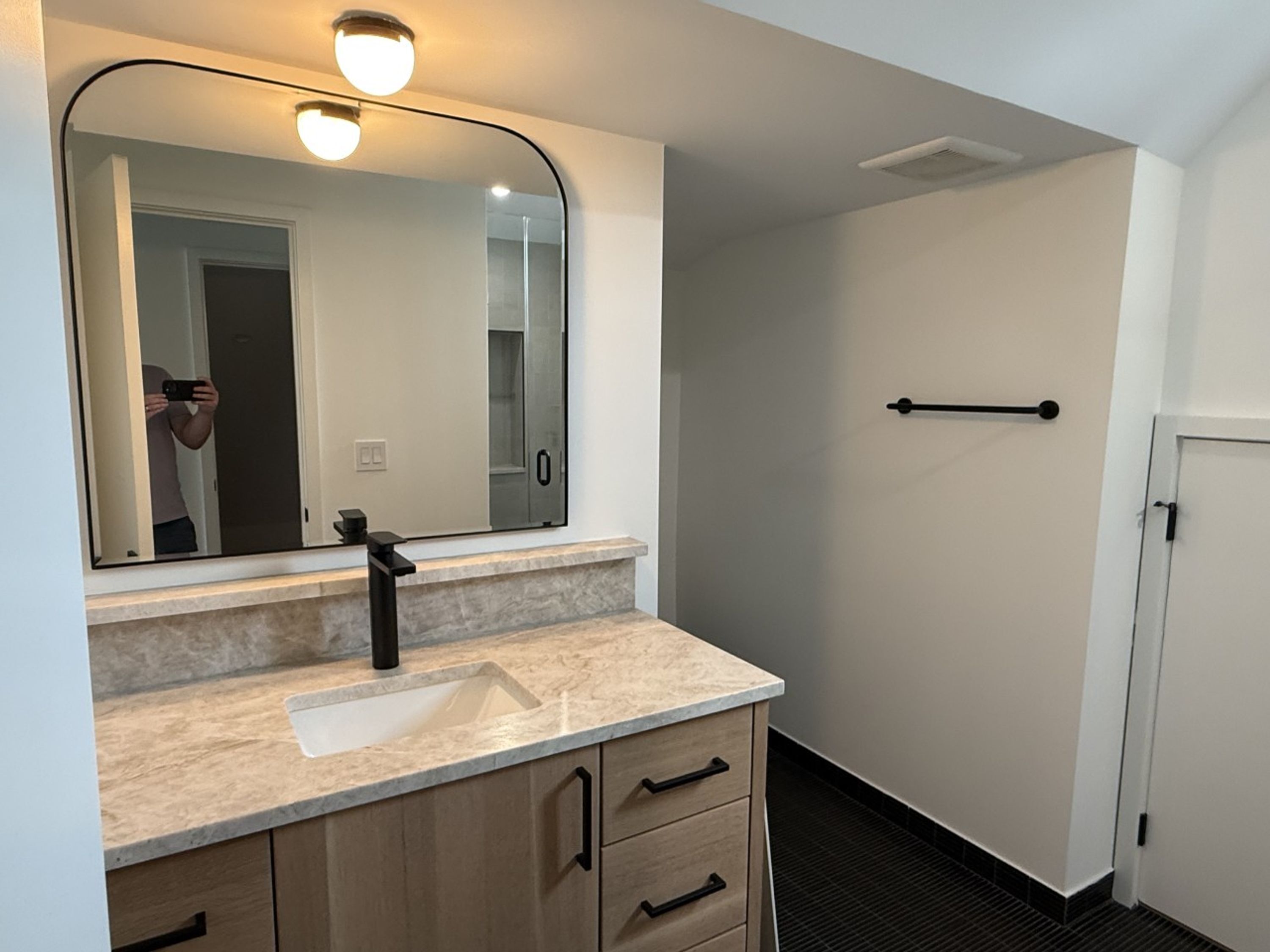 A bathroom with a sink, mirror, and a towel rack.