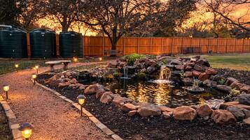 A garden with a pond, rocks, and a wooden fence.