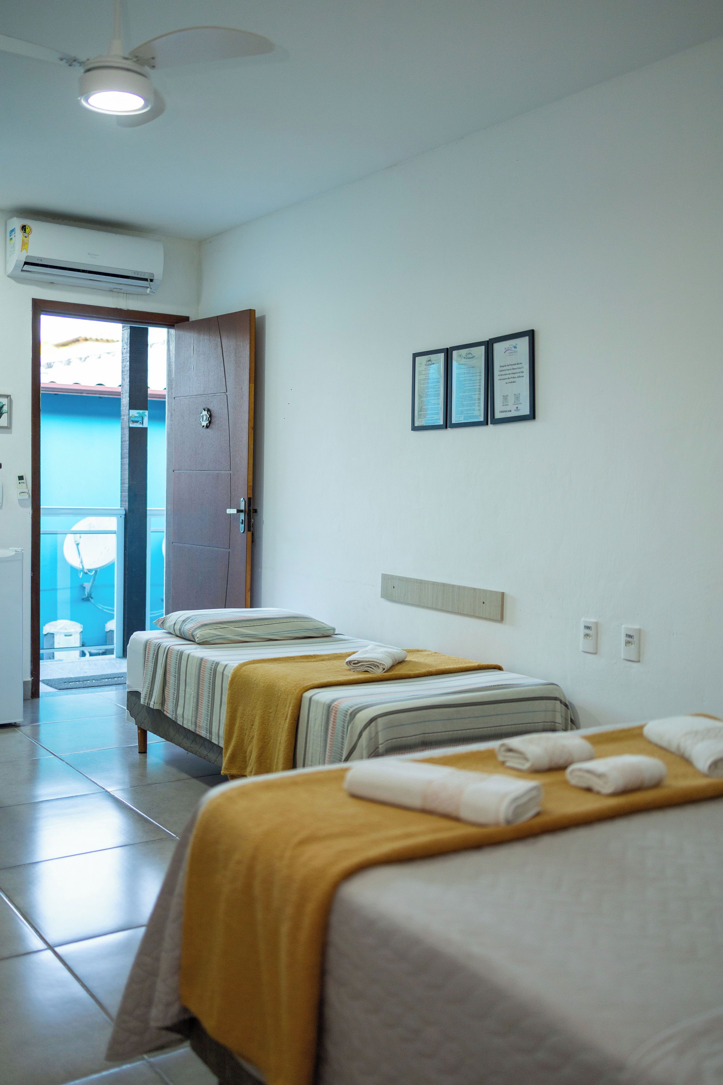 A hotel room with two beds, a door leading to a balcony, and an air conditioning unit.