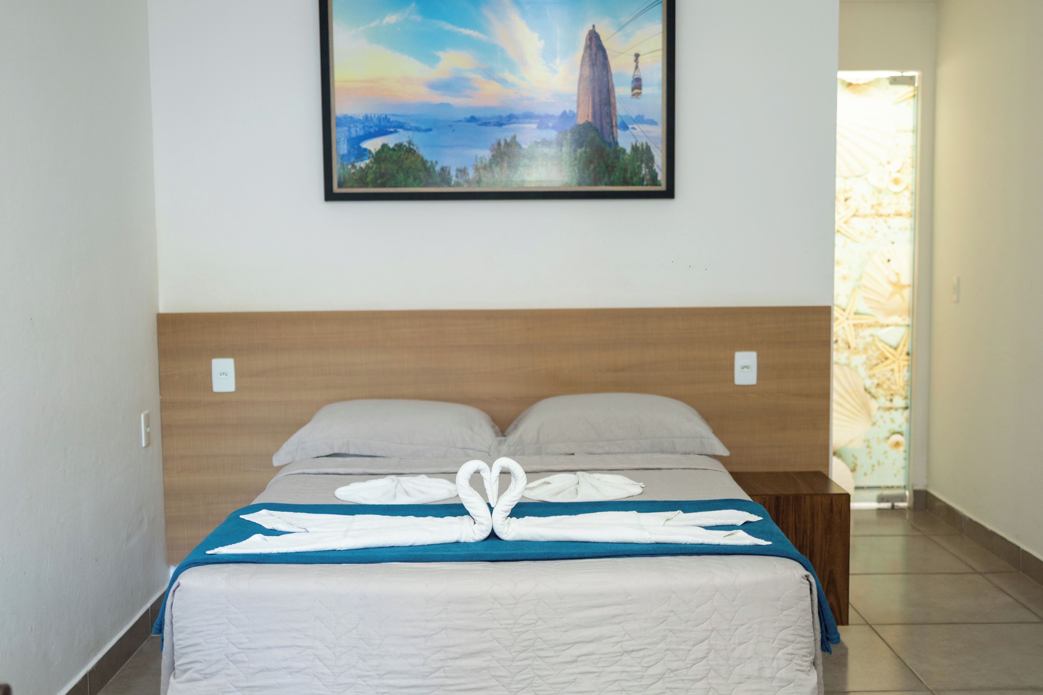 Ein Hotelzimmer mit einem Bett, einem Landschaftsbild und einem Fenster mit Ausblick.