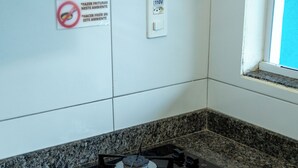 A kitchen with a granite countertop, four burners, a stove, a prohibition sign, and a power outlet.