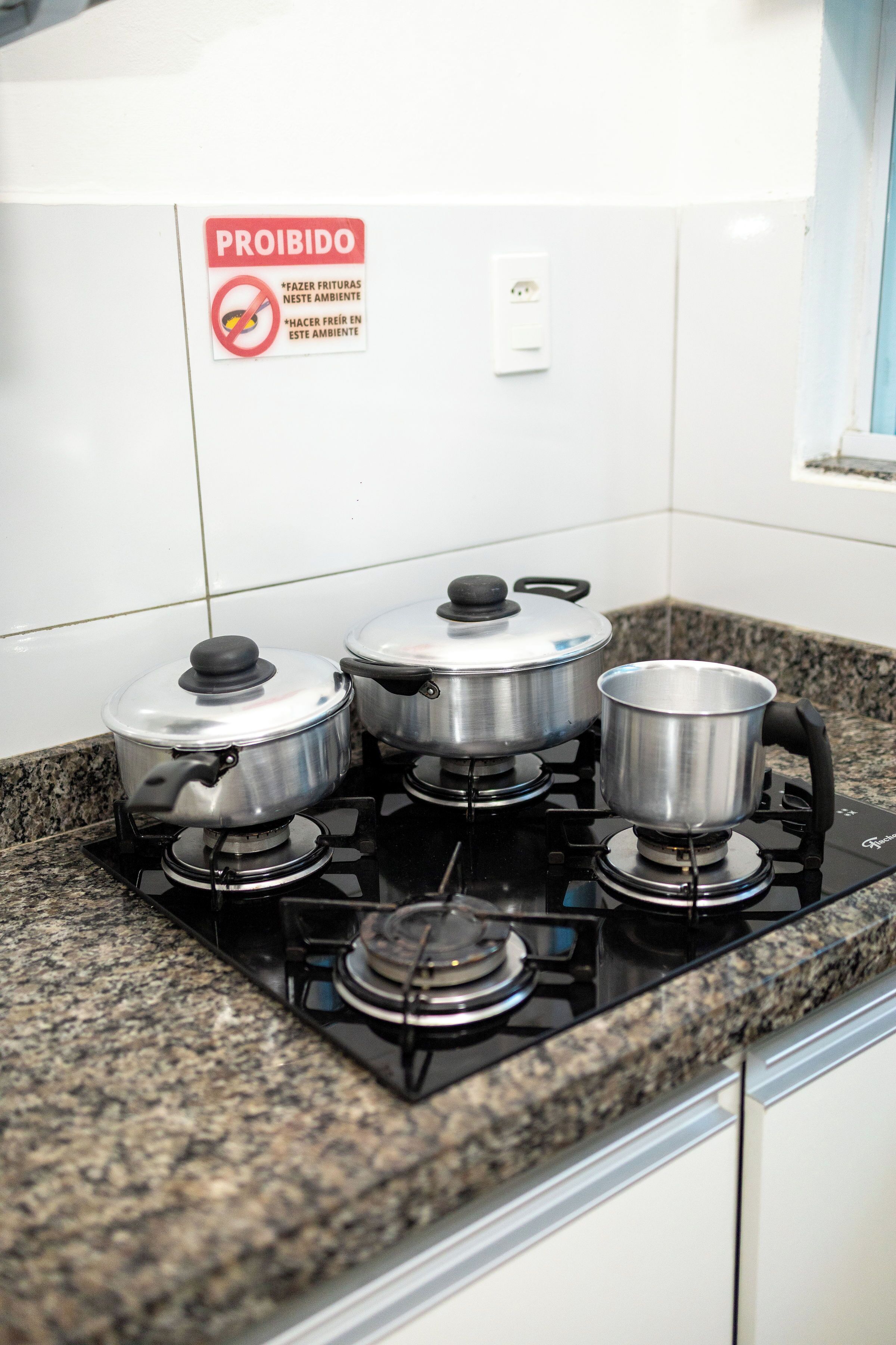 Una cucina con un fornello a gas e tre pentole sopra.