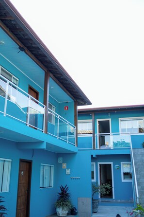 A two-story building with a blue exterior, a wooden door, and a balcony with a glass railing. - Di Villa Búzios (Buzios)