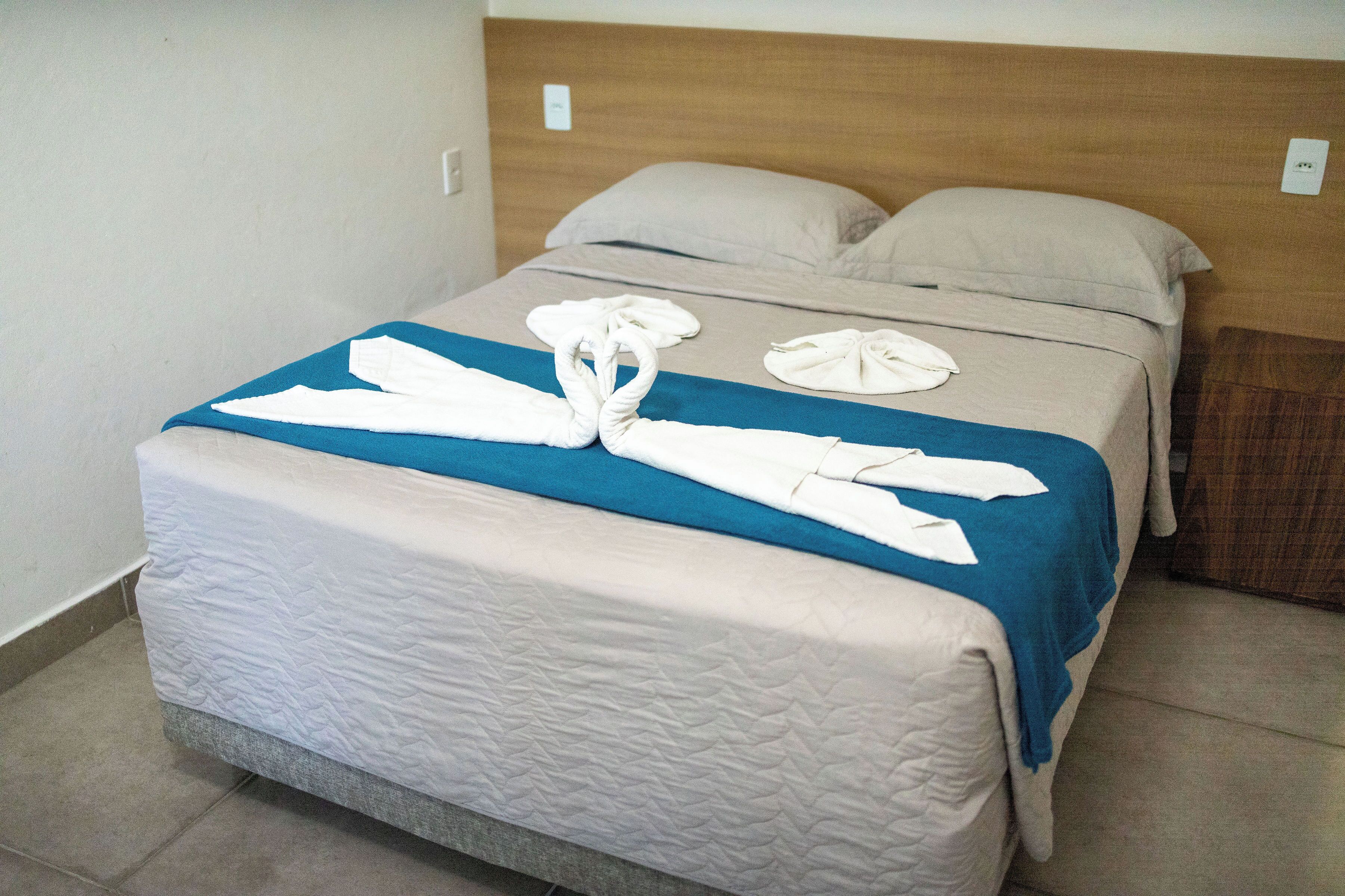 A bed with a blue blanket, white towels, and a wooden headboard.