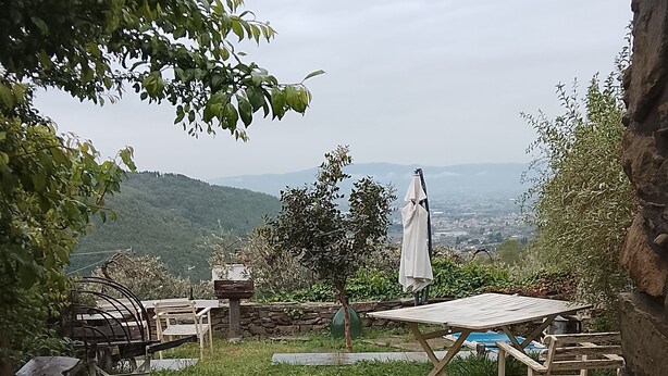 A stone patio with a view of a city in the distance, surrounded by greenery and a stone wall. - La Cannicciaia "Historic House Near Florence" (Tobbiana)