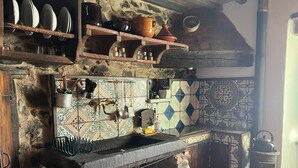A rustic kitchen with stone walls, a tiled backsplash, and a traditional stove. - La Cannicciaia "Historic House Near Florence" (Tobbiana)