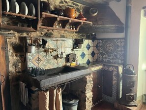 Eine rustikale Küche mit Steinwänden, einer Fliesenrückwand und einem traditionellen Herd.