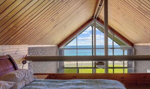 A bedroom with a large window, wooden ceiling, and a view of the beach. - South Beach Absolute Beach Front.  Pet friendly! (Carrickalinga)