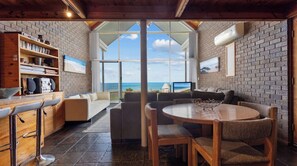A modern interior with a kitchen, dining area, and seating with a view of the ocean. - South Beach Absolute Beach Front.  Pet friendly! (Carrickalinga)