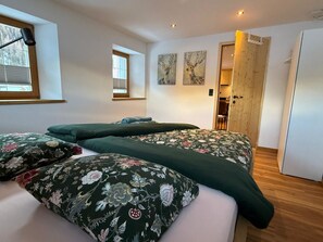 A room with two beds, a window, and a door leading to another room. - Chasa Salnuun, (Samnaun-Compatsch) by Interhome (Samnaun)