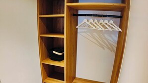 Um closet espaçoso com prateleiras de madeira, cabides e um pequeno banco.